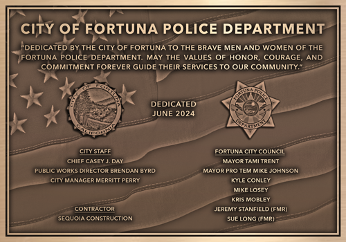 A cast bronze police department dedication plaque mounted at a station entrance.